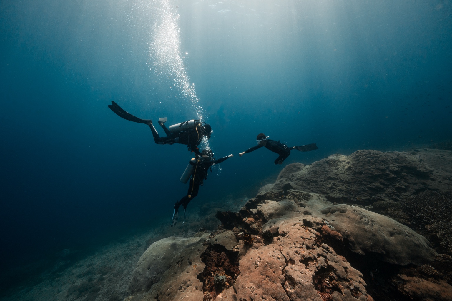 Freediver interacting with scuba divers underwater